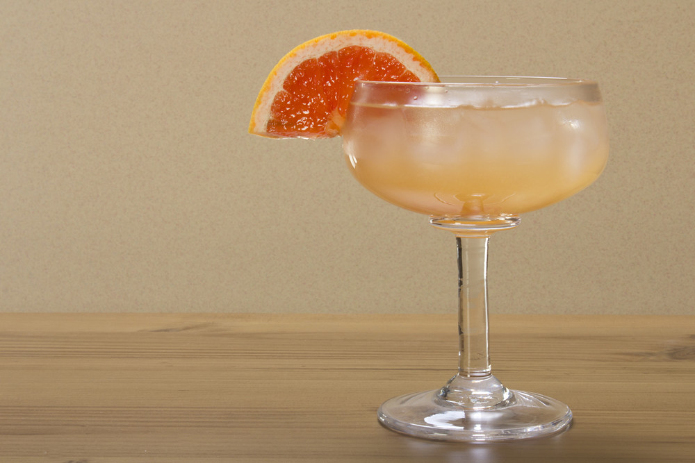A cocktail with an orange on the rim.