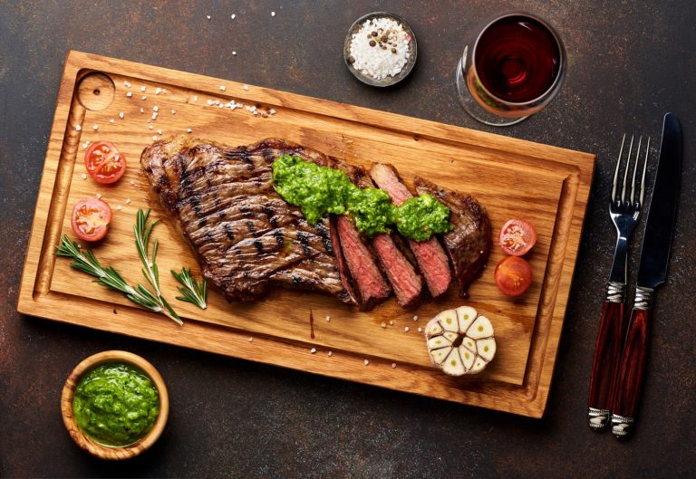 Grilled steak and a glass of red wine with chimichurri sauce.