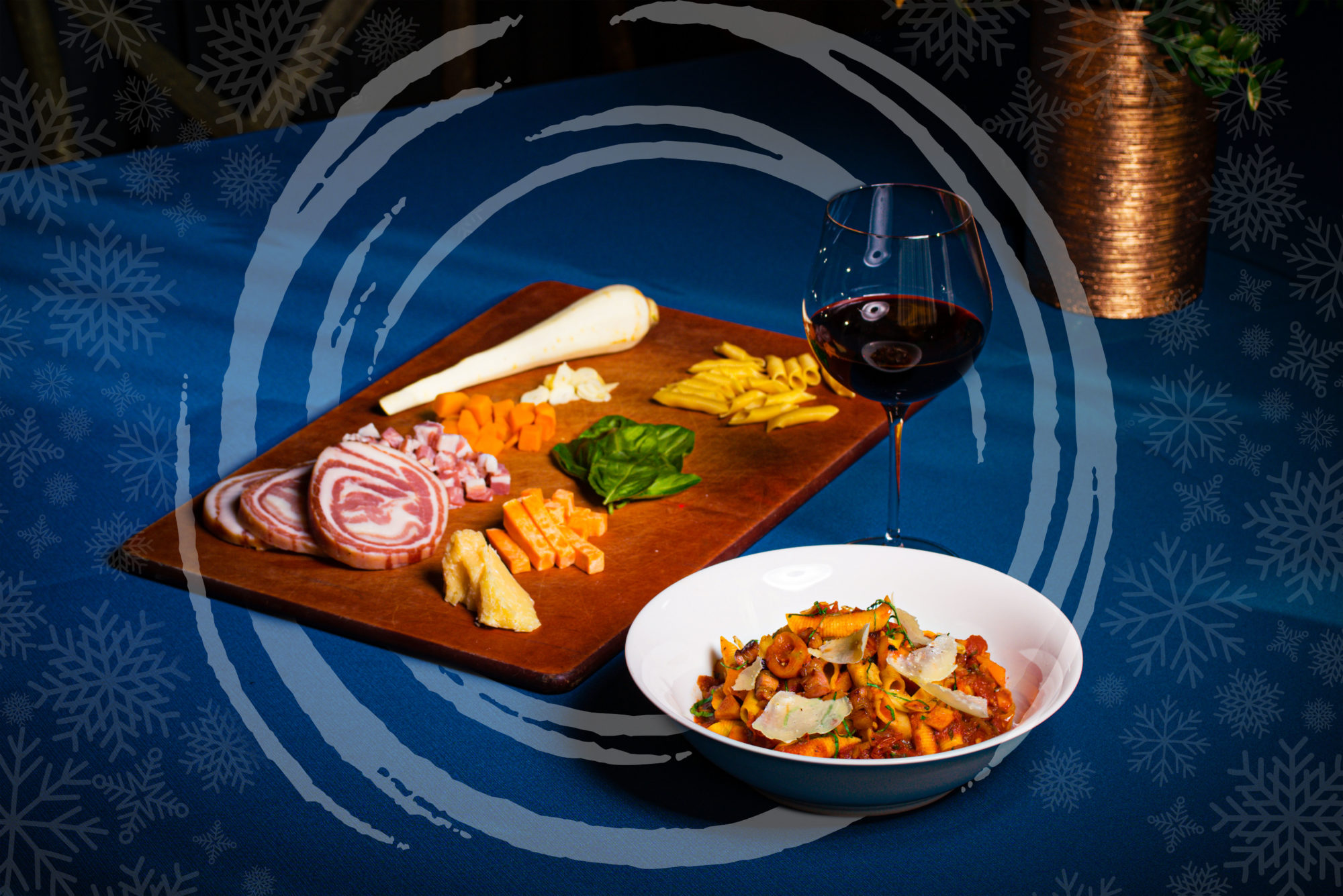 A charcuterie board with a bowl of pasta and a glass of wine next to it.
