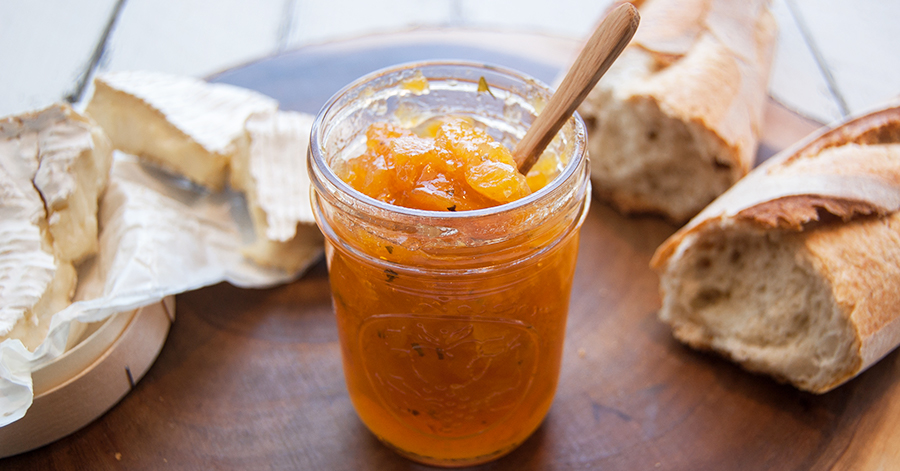 Jam in a mason jar, with bread in the back.