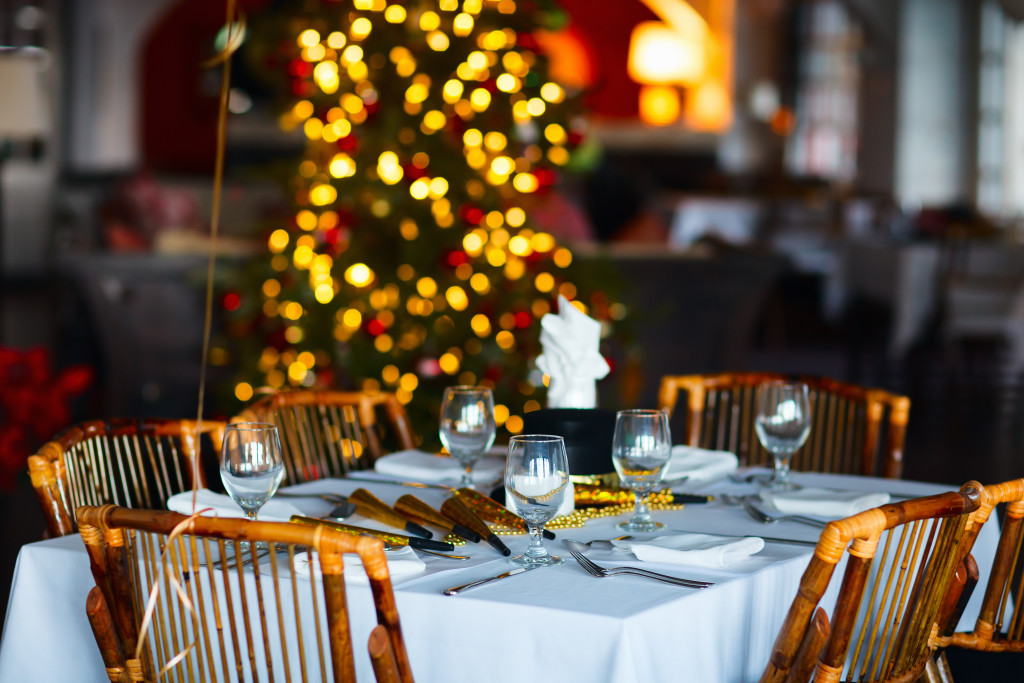 A table setting with a christmas tree in the back for a holiday party.
