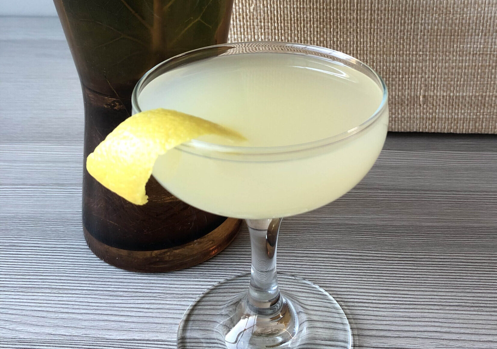 Yellow bee's knees cocktail in coupe glass with lemon peel